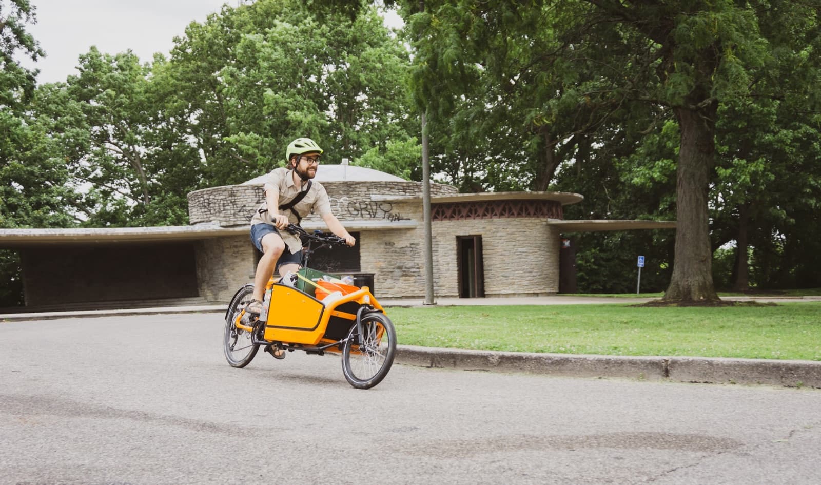 A Larry vs Harry Bullitt cargo bike with a mid-drive electric conversion, loaded up and riding through a Cincinnati park